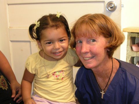 Miss Peggy smiling at the camera with a young Honduran child